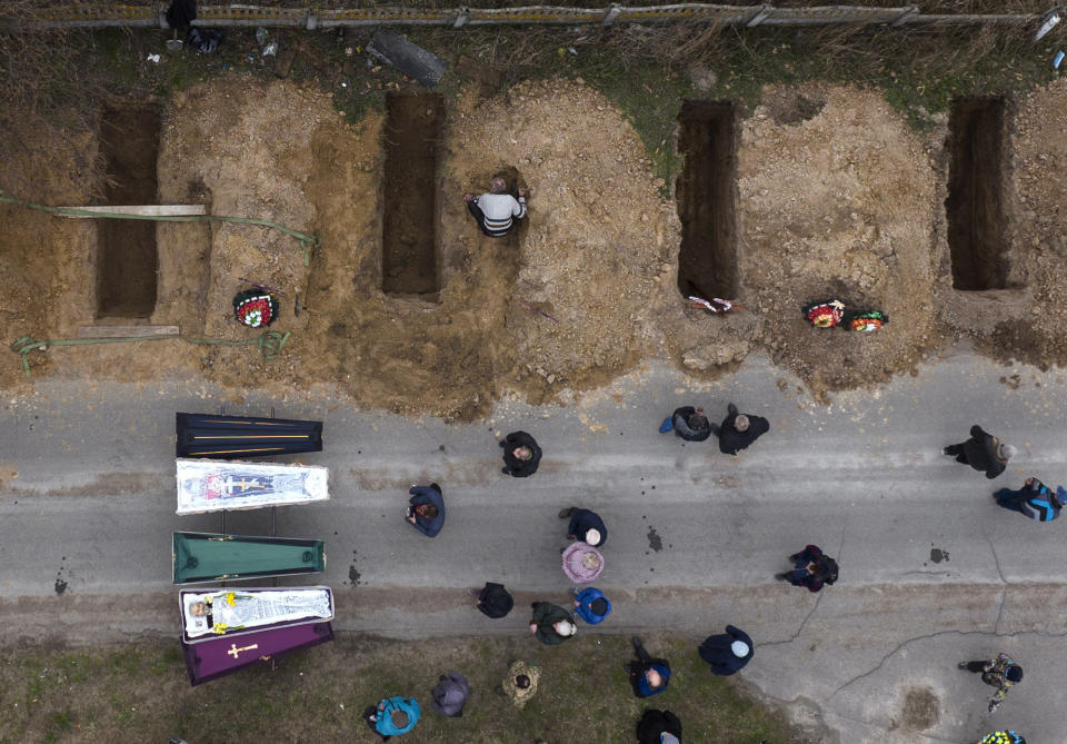 FILE - The bodies of four people who died during the Russian occupation await burial during funerals in Bucha, on the outskirts of Kyiv, on April 20, 2022. Many Americans continue to question whether President Joe Biden is showing enough strength in response to Russia’s war against Ukraine, even as most approve of steps the U.S. is already taking and few want U.S. troops to get involved in the conflict. (AP Photo/Emilio Morenatti, File)