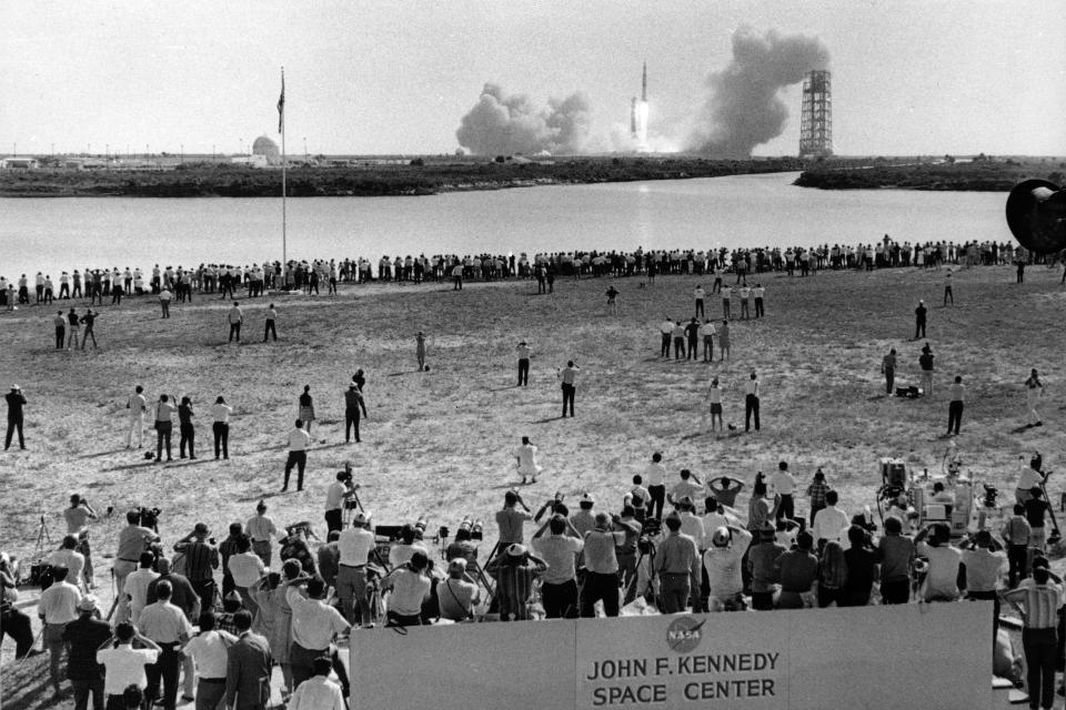 FILE - In this July 16, 1969 file photo, reporters line the banks of a lagoon at the Cape Kennedy Press Site in Cape Canaveral as the Saturn V rocket with Apollo 11 astronauts aboard launches three-and-a-half miles away on their historic mission to the moon. (AP Photo)