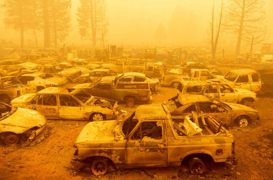 Dozens of burned vehicles rest in heavy smoke during the Dixie fire in Greenville, California on Aug. 6, 2021.