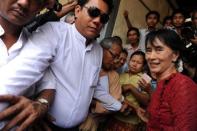 Myanmar opposition leader Aung San Suu Kyi (R) is surrounded by supporters and journalists as she leaves a polling station in the constituency where she is standing as a candidate in Kawhmu on April 1, 2012