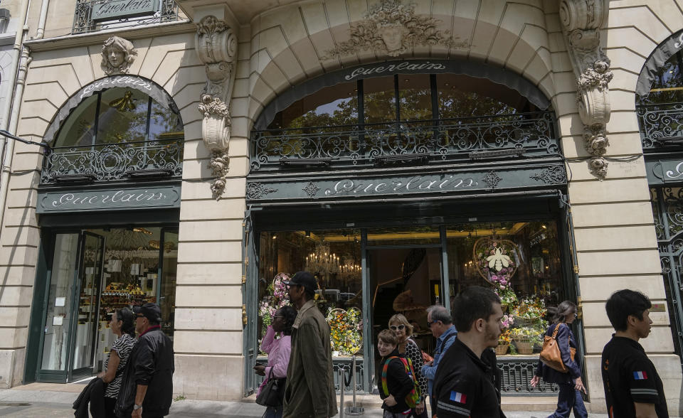 People walk past the Guerlain boutique at the Champs-Elysees avenue in Paris, Tuesday, May 30, 2023. Guerlain, the house which invented modern perfumery, has for the first time in its history created an archive to delve into its pioneering and history making past. (AP Photo/Michel Euler)