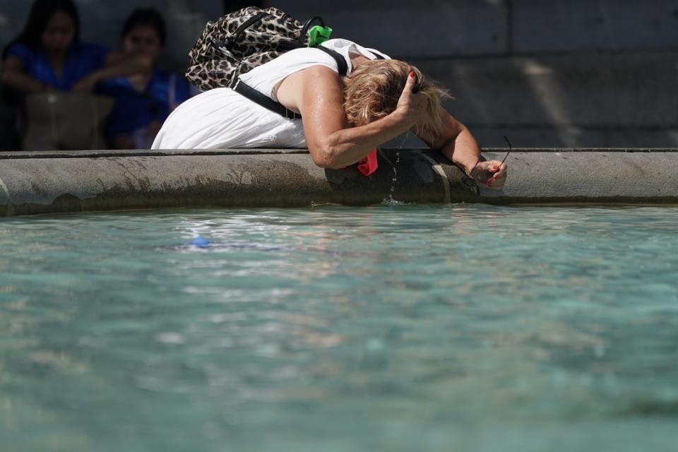 A person wets their hair in a fountain at Trafalgar Square in central London (Aaron Chown/PA) (PA Wire)