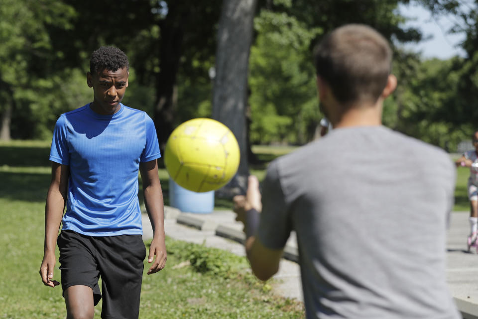 Belachew Neal, left, runs soccer drills with his dad, Paul, at Garfield Park, Sunday, June 14, 2020, in Indianapolis. The Associated Press discussed race with six white couples who have adopted or have custody of Black children. These parents are trying to help their children understand race in America while getting an accelerated course themselves.(AP Photo/Darron Cummings)