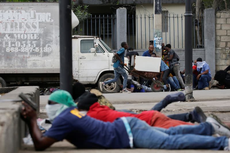 A street vendor pushes a wheelbarrow as he runs away during a shooting in Champ de Mars, Port-au-Prince