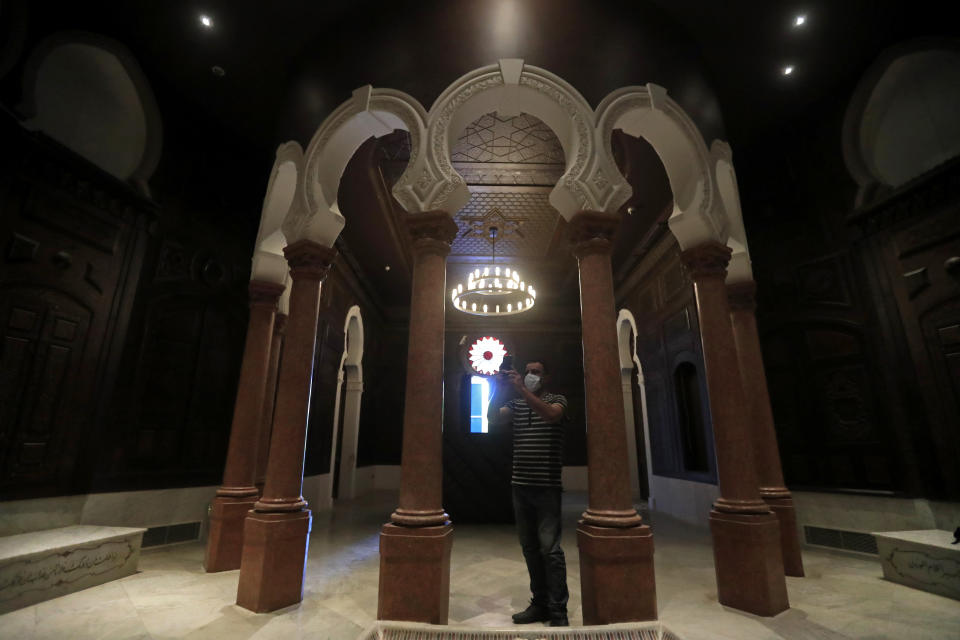 A museum worker takes pictures on a mobile phone of one of the reconstructed halls at the Sursock Museum that was damaged from the massive explosion in the nearby Beirut port, in Beirut, Lebanon, July 27, 2021. Lebanon's only modern art museum is still rebuilding a year after the explosion decimated it. (AP Photo/Hussein Malla)