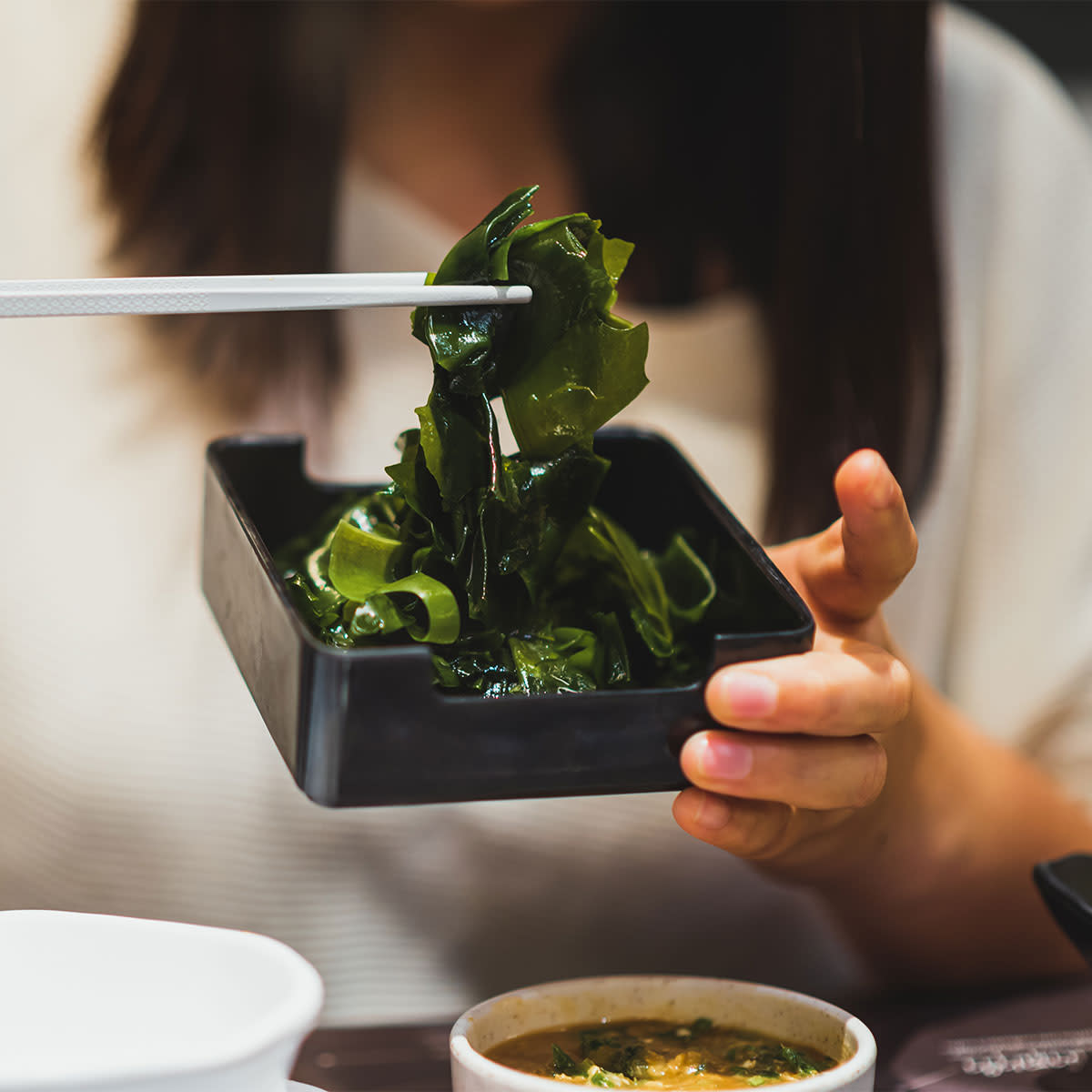 woman eating seaweed with chopsticks