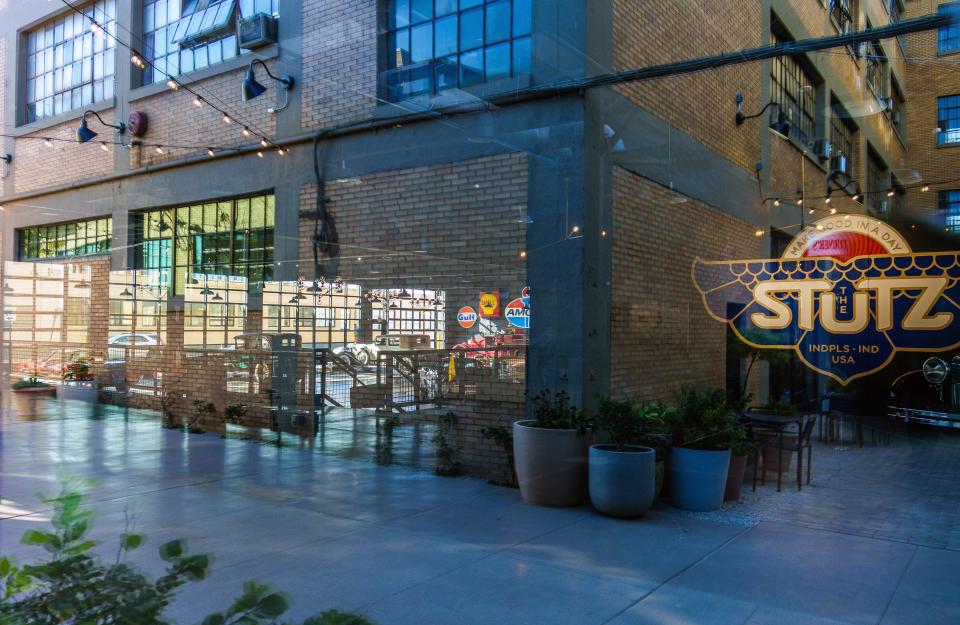 Outdoor seating sits in the reflection of a window near The Stutz's car museum Friday, Nov. 10, 2023, at the newly renovated building offering food and dining, office and retail space in Indianapolis.