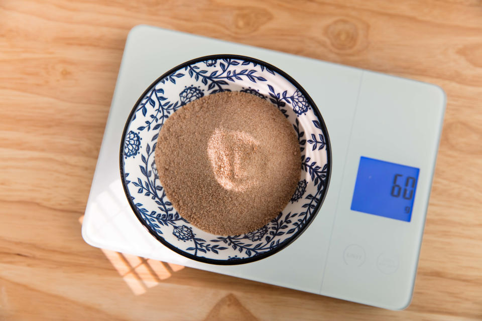 A patterned bowl filled with a fine granular substance weighs 60g on a digital kitchen scale