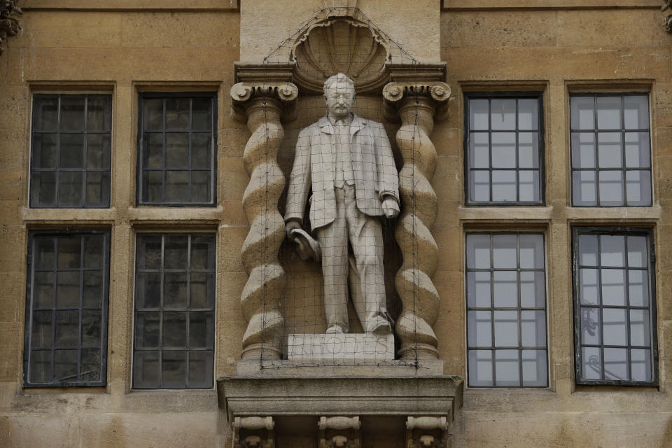 A statue of Cecil Rhodes, the controversial Victorian imperialist who supported apartheid-style measures in southern Africa stands mounted on the facade of Oriel College in Oxford, England, Wednesday, June 17, 2020. The governing body of Oriel College are meeting today to discuss the future of the statue. (AP Photo/Matt Dunham)