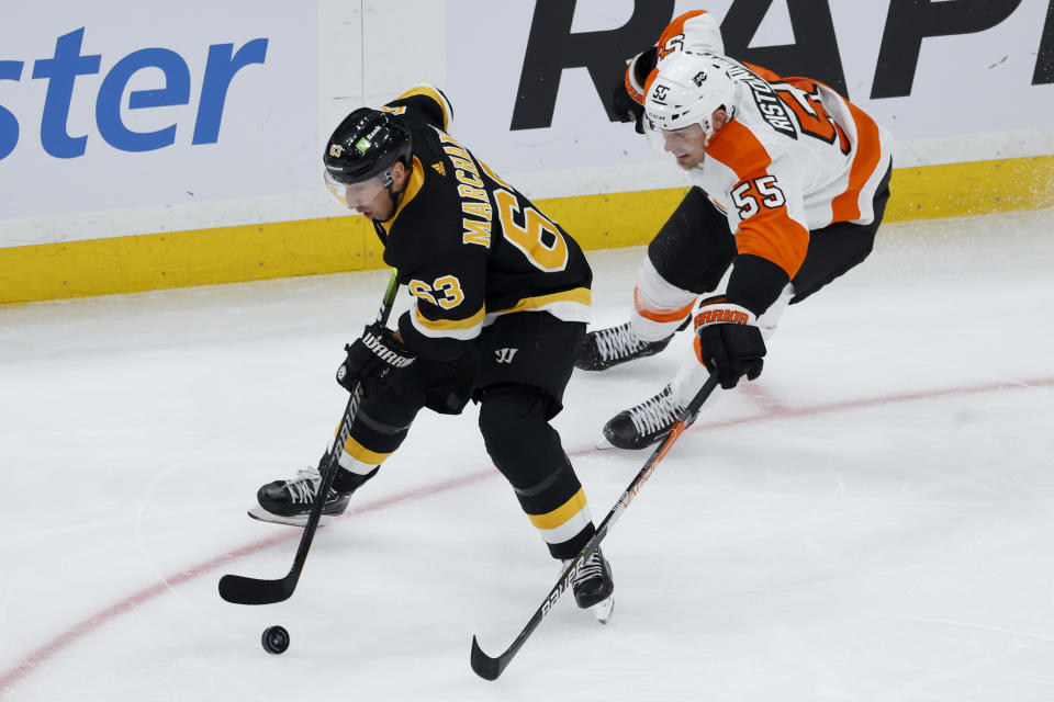 Boston Bruins left wing Brad Marchand controls the puck ahead of Philadelphia Flyers defenseman Rasmus Ristolainen (55) during the first period of an NHL hockey game, Monday, Jan. 16, 2023, in Boston. (AP Photo/Mary Schwalm)