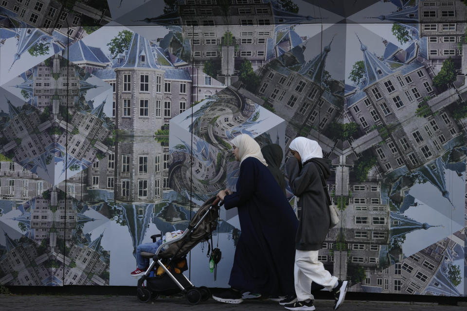 Pedestrians pass a scaffolding with a kaleidoscope image of the parliament under renovation, one day after Wilders' far-right party PVV, or Party for Freedom, won the most votes in a general election, in The Hague, Netherlands, Thursday Nov. 23, 2023. (AP Photo/Peter Dejong)