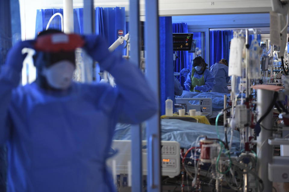 Members of the clinical staff wearing Personal Protective Equipment PPE care for a patient with coronavirus in the intensive care unit at the Royal Papworth Hospital in Cambridge, England, Tuesday May 5, 2020. (Neil Hall/Pool via AP)