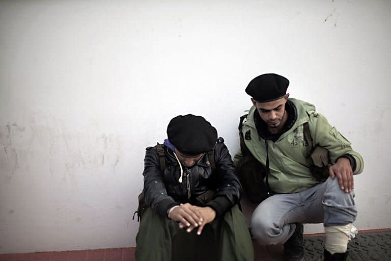 Libyan rebel fighters wait for news of wounded comrades at the morgue of Brega's hospital where bodies have been brought out from the battle of Ras Lanuf
