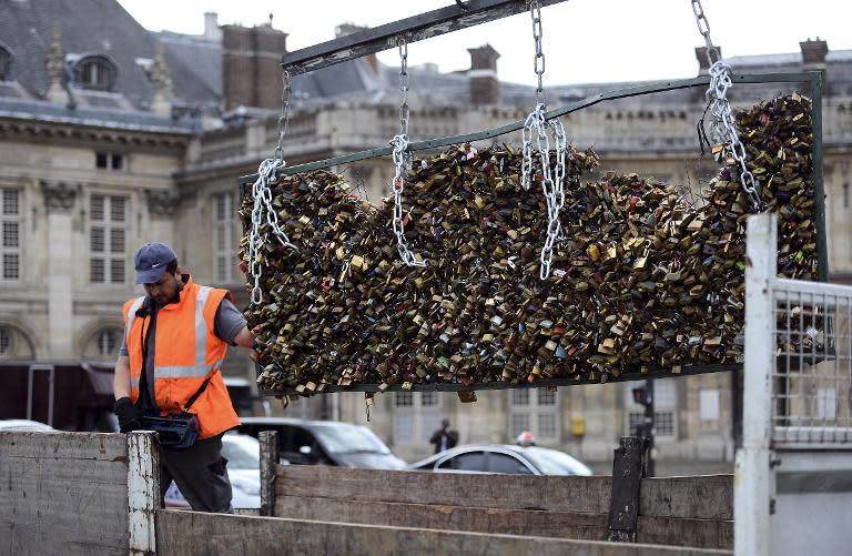 A worker removes love padlocks attached on the railings of the Pont des Arts in Paris, on June 1, 2015