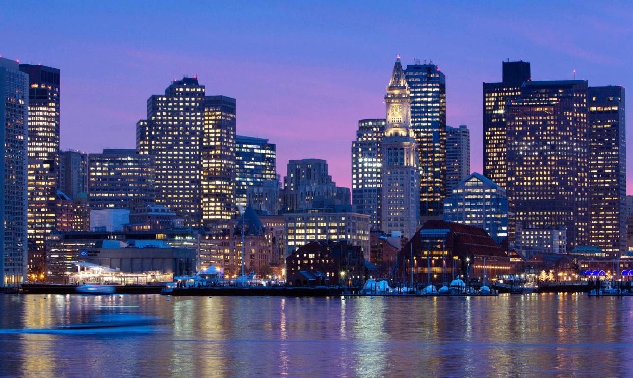 In this Jan. 6, 2012 file photo, the Boston city skyline is illuminated at dusk as it reflects off the waters of Boston Harbor.