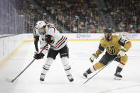 Chicago Blackhawks center Connor Bedard (98) passes around Vegas Golden Knights center Nicolas Roy (10) during the first period of an NHL hockey game Tuesday, April 16, 2024, in Las Vegas. (AP Photo/Ian Maule)