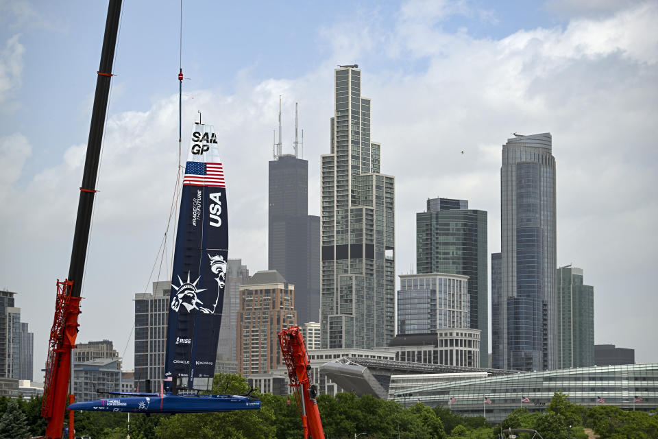 In this image provided by SailGP, the Chicago skyline including the Willis Tower and Soldier Field is seen behind the USA SailGP Team F50 catamaran as it's craned onto the water ahead of T-Mobile United States Sail Grand Prix, Wednesday June 15, 2022, in Chicago. (Ricardo Pinto/SailGP via AP)