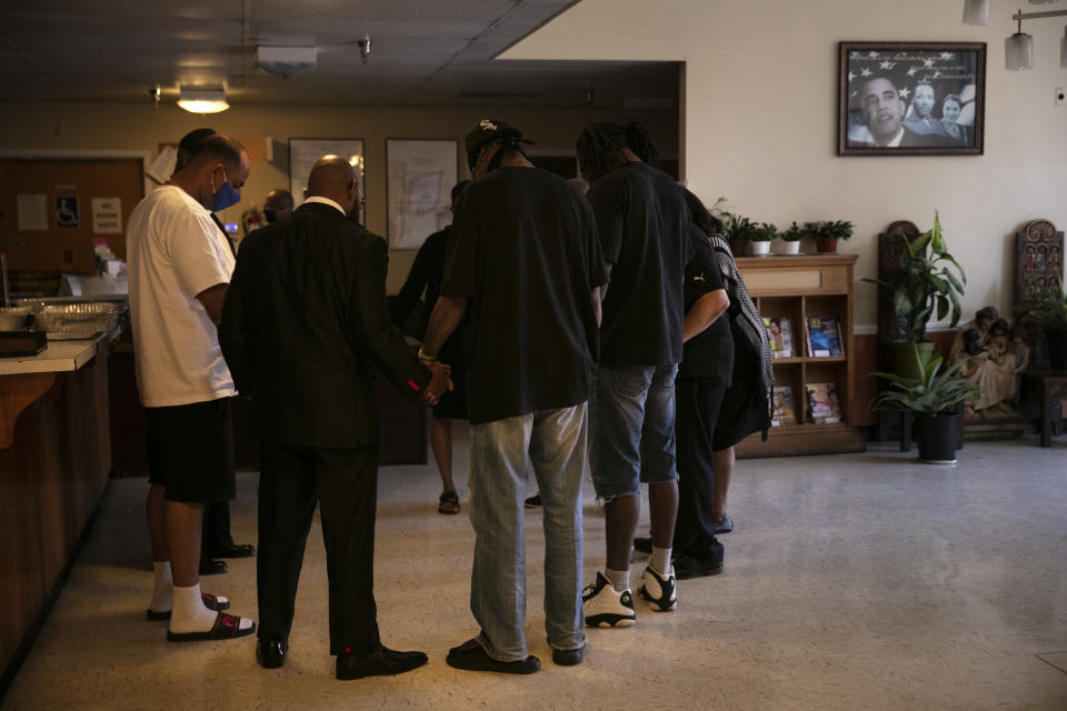 The Rev. Marcus Murchinson, second from left, and his church members pray with rehab residents after donating homemade cakes to celebrate Father's Day, Sunday, June 21, 2020, in the Watts neighborhood of Los Angeles. Churches are the heart of the Black community, Murchinson said. In addition to ministering to the faithful, churches provide food, clothing and recreation programs for children. Murchinson also runs a charter school and drug rehab clinics. (AP Photo/Jae C. Hong)