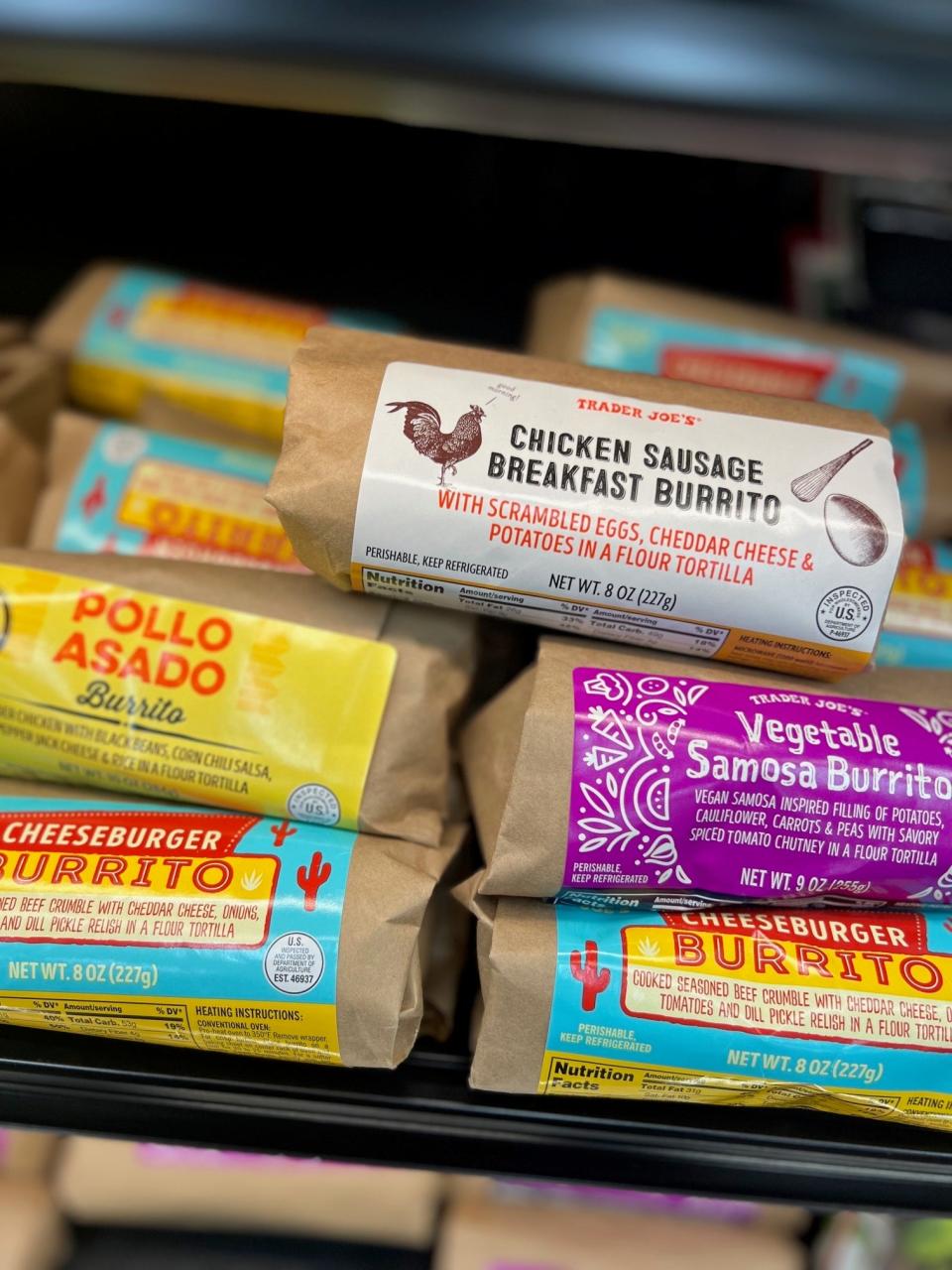 Shelf with various Trader Joe's burritos, including chicken, pollo asado, and vegetable samosa