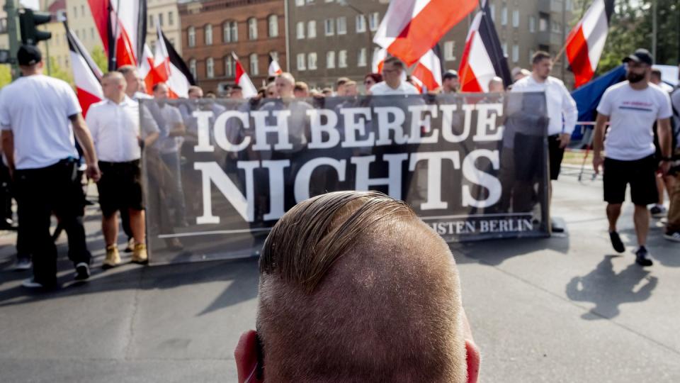 Vor dem Zug der Neonazi-Demonstration anlässlich des 31. Todestages von Rudolf Heß kniet ein Mann mit einer Fisur, die bei Neonazis üblich ist. Foto: dpa