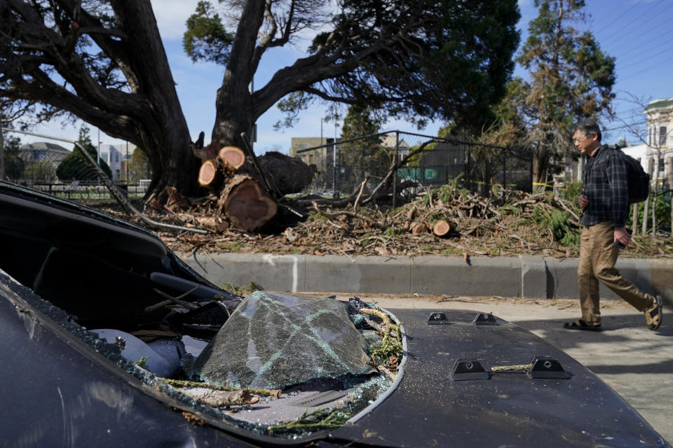 Damage to a vehicle crushed by a tree downed by high winds can be seen in San Francisco, Wednesday, Feb. 22, 2023. A brutal winter storm knocked out power in California, closed interstate highways from Arizona to Wyoming and prompted more than 1,200 flight cancellations Wednesday — and the worst won't be over for several days. (AP Photo/Godofredo A. Vásquez)