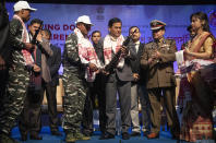 Assam Chief minister Sarbananda Sonowal, third from right, receives arms from one of the rebels who surrendered during a ceremony in Gauhati, India, Thursday, Jan. 23, 2020. More than 600 insurgents belonging to eight different rebel groups have surrendered to Indian authorities in this troubled northeastern state, responding to the government’s peace initiative to rejoin mainstream society. (AP Photo/Anupam Nath)