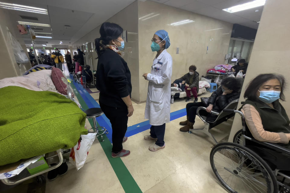 A medical worker talks to a woman as elderly patients receive intravenous drips along a corridor in the emergency ward of a hospital in Beijing, Thursday, Jan. 5, 2023. Patients, most of them elderly, are lying on stretchers in hallways and taking oxygen while sitting in wheelchairs as COVID-19 surges in China's capital Beijing. (AP Photo/Andy Wong)