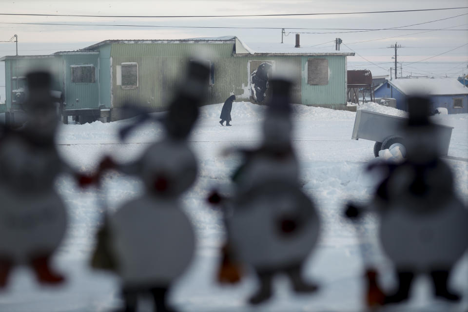 A woman walks along a road as paper snowmen adorn a school window Saturday, Jan. 18, 2020, in Toksook Bay, Alaska. The first Americans to be counted in the 2020 Census starting Tuesday, Jan. 21, live in this Bering Sea coastal village. The Census traditionally begins earlier in Alaska than the rest of the nation because frozen ground allows easier access for Census workers, and rural Alaska will scatter with the spring thaw to traditional hunting and fishing grounds. (AP Photo/Gregory Bull)