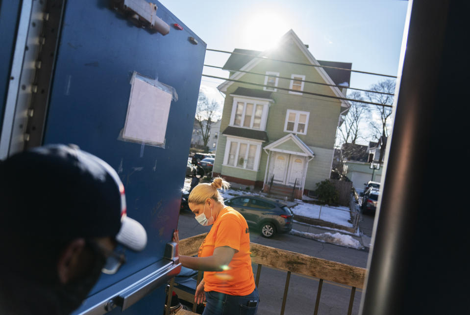 Mayor Maria Rivera holds the door open for a patient after they received a vaccine at a clinic in Central Falls, R.I., Saturday, Feb. 6, 2021. Rivera says she's already dreaming of the return of beloved community events, like the city's summertime salsa nights. "I would love to get back to our pre-pandemic life," she said while volunteering recently at the high school site. "I'm looking forward to the day we don't have to wear face masks." (AP Photo/David Goldman)