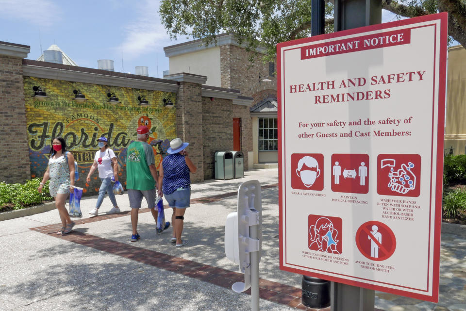 FILE - In this June 16, 2020, file photo, signs remind patrons to wear masks and other protocols because of the coronavirus pandemic as they stroll through the Disney Springs shopping, dining and entertainment complex in Lake Buena Vista, Fla. On Friday, June 26, Vice President Mike Pence said Americans should look to their state and local leadership for modeling their behavior during the coronavirus pandemic. The comments only days after President Donald Trump held two campaign events that drew hundreds of participants but few wearing masks. (AP Photo/John Raoux, File)