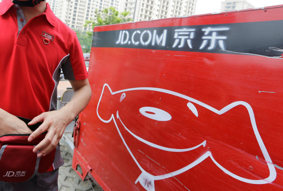 A JD.com delivery tricycle is seen next to a delivery man in Beijing, China June 16, 2014. Picture taken June 16, 2014. REUTERS/Jason Lee