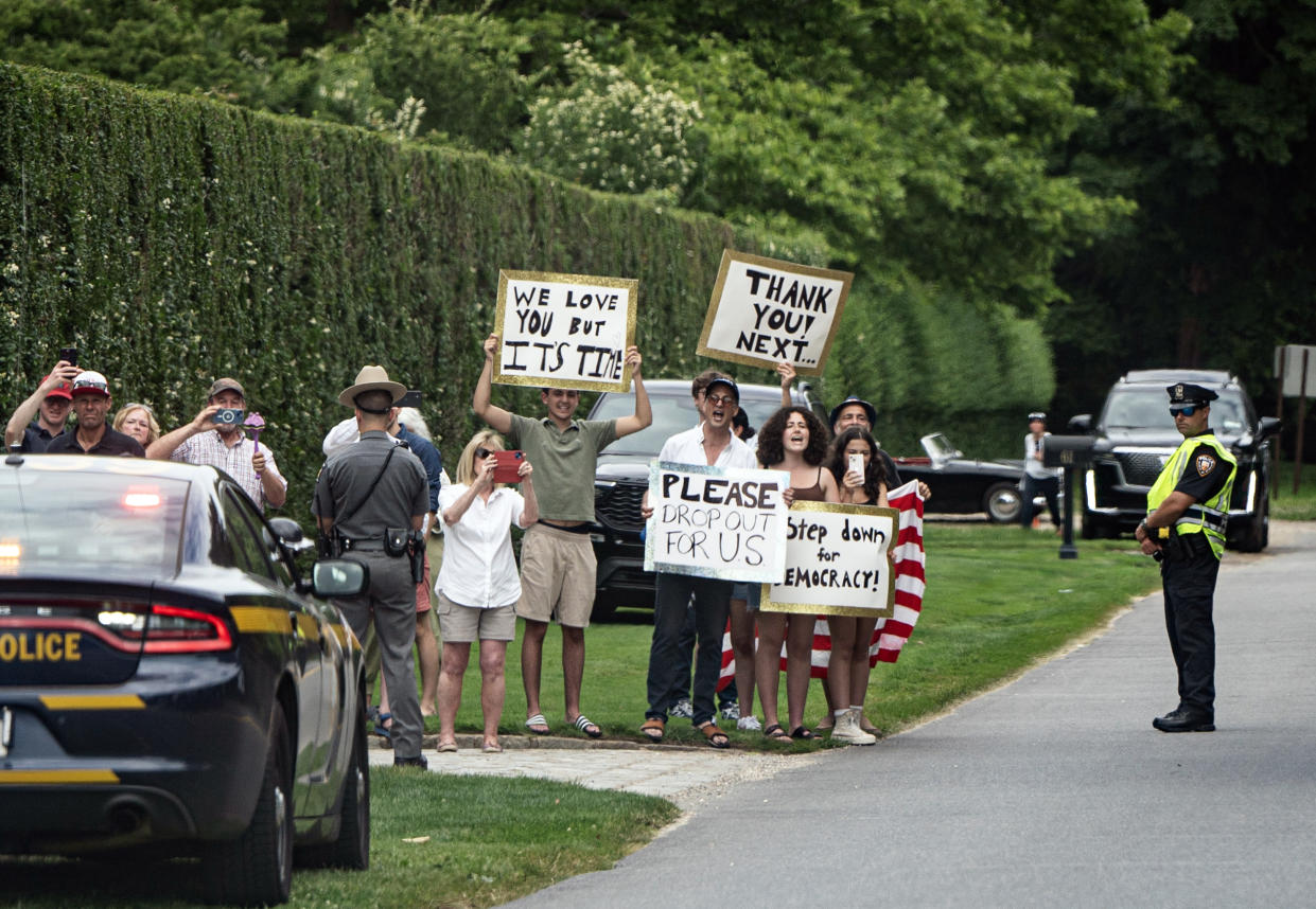 People hold signs calling for President Joe Biden to step aside this upcoming election in East Hampton, N.Y., as the motorcade carrying President Joe Biden and First Lady Dr. Jill Biden en route to a campaign reception on Saturday, June 29, 2024. (Haiyun Jiang/The New York Times)