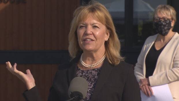 Ontario Health Minister Christine Elliott, left, speaks to reporters outside the Pine River Institute in Mulmur, Ont. at a news conference on Monday. Edyta Pacuk, chair of the facility's board, right, stands behind her. (CBC - image credit)