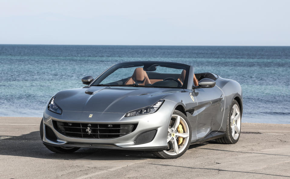 A silver Ferrari Portofino, a sleek front-engined convertible sports car, parked on a beach.