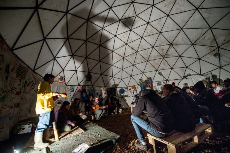 Migrants attend a concert in a makeshift theatre in the so-called "Jungle" migrant camp in Calais, northern France on November 25, 2015