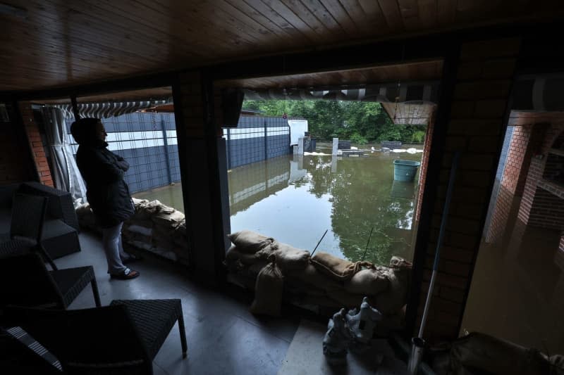 A woman stands in a conservatory in front of her garden, which has been flooded by the Mindel. Karl-Josef Hildenbrand/dpa