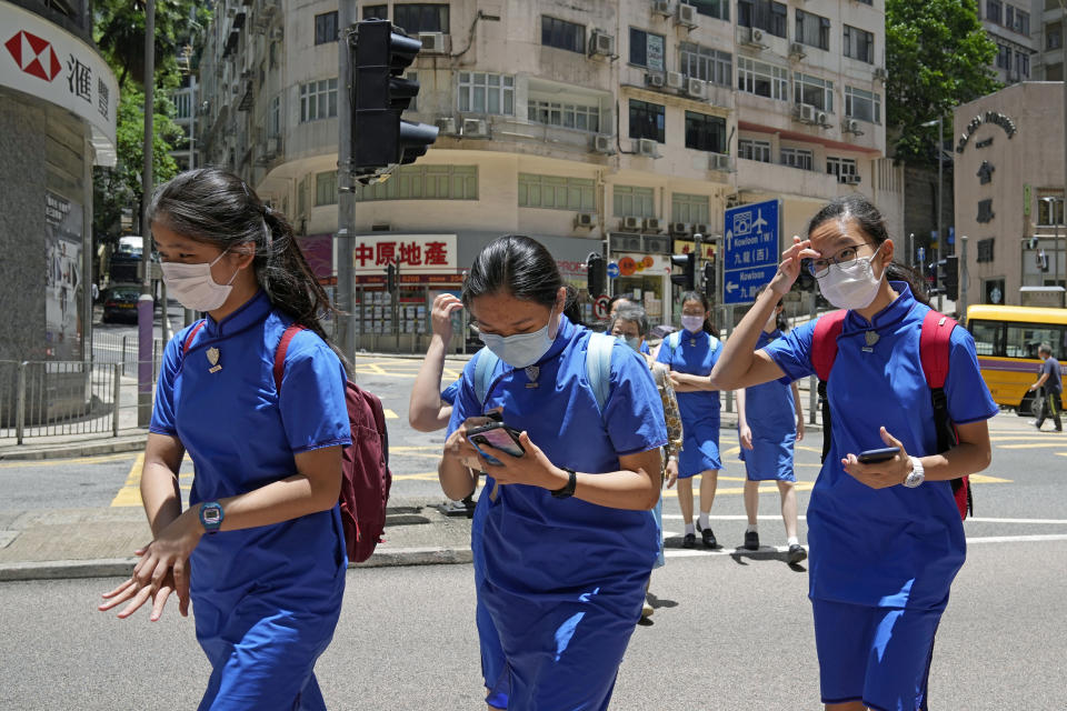 Students wearing face masks to prevent the spread of coronavirus, walk across a street in Hong Kong, Thursday, June 10, 2021. Government officials said Thursday that they will expand the vaccination drive to about 240,000 children from 12 to 15 years old starting Friday, joining other countries such as Singapore and the U.S. that have started vaccinating children. (AP Photo/Kin Cheung)
