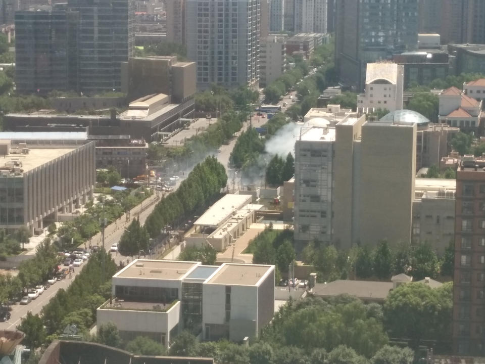 <p>Smoke rises from the street corner near the U.S. Embassy in Beijing, China, July 26, 2018 in this image obtained from social media. (Photo: Jin Song via Reuters) </p>