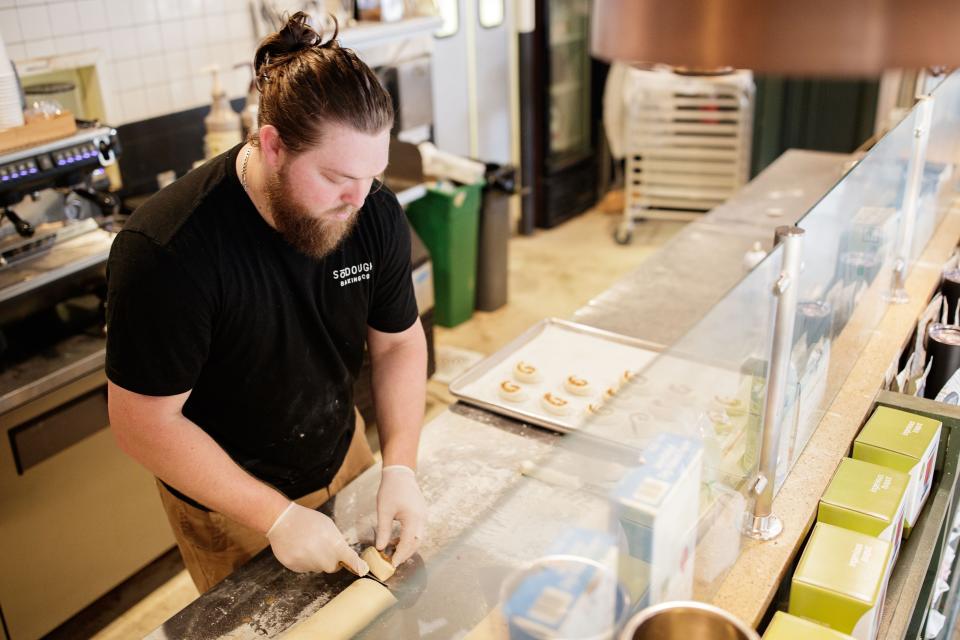 Chris Leduc, co-owner of SōDOUGH Baking Co. with his wife, cuts cinnamon rolls Thursday, Feb. 3, 2022.