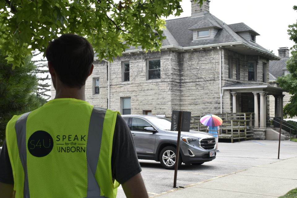 Matthew Harper, 24, of Louisville, came to Bloomington Thursday to protest abortion. He was outside the city's Planned Parenthood clinic representing a group called Speak for the Unborn. A man who volunteers as a Planned Parenthood escort for patients stands in the background beneath an umbrella in the hot late-morning sun.