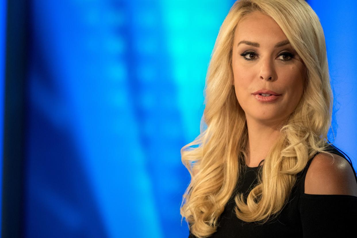 Fox Host Britt McHenry looks off to the right of the camera wearing a black top revealing her shoulders.