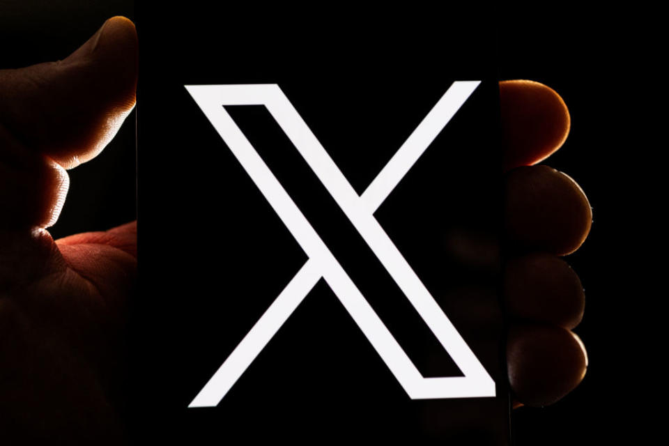 A hand is holding a device displaying a white "X" on a black screen. The image is featured in an article categorized as Internet Finds