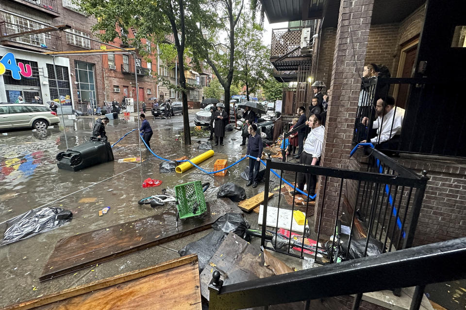 Residents watch as workers attempt to clear a drain in flood waters, Friday, Sept. 29, 2023, in the Brooklyn borough of New York. A potent rush-hour rainstorm has swamped the New York metropolitan area. The deluge Friday shut down swaths of the subway system, flooded some streets and highways, and cut off access to at least one terminal at LaGuardia Airport. (AP Photo/Jake Offenhartz)