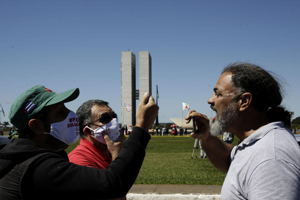 A supporter of President Jair Bolsonaro and opponents argue during a protest demanding President Jair Bolsonaro be impeached, in front of the National Congress in Brasilia, Brazil, Thursday, May 21, 2020. As Brazil careens toward a full-blown public health emergency and economic meltdown, opponents have filed a request for Bolsonaro's impeachment based on his mishandling of the new coronavirus pandemic. (AP Photo/Eraldo Peres)