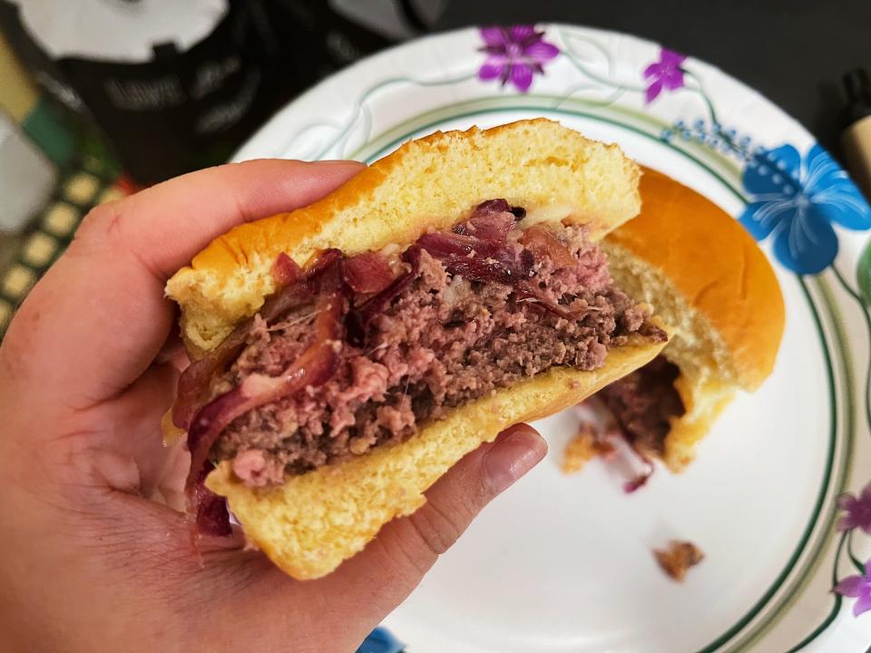 a person holding half of a burger