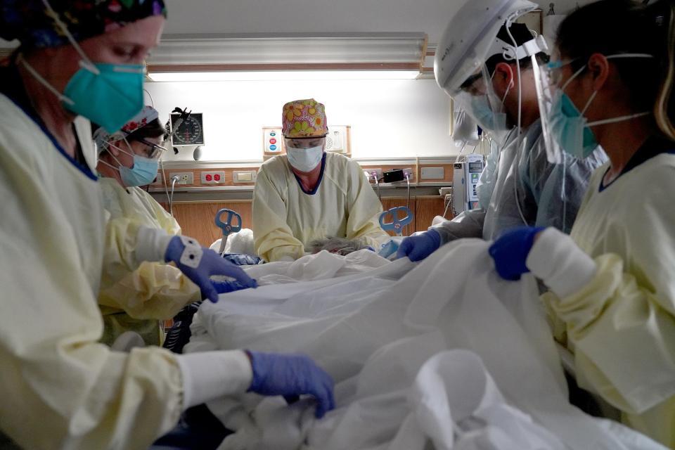 Respiratory therapist Julie Medeiros, center, and intensive care nurses prepare to "prone" a patient on Tuesday, Feb. 9, 2021, at Providence Holy Cross Medical Center in Los Angeles. ICU nurses prone, or flip, a patient on their stomach or back every two hours to allow better expansion of the lungs, ultimately leading to improved oxygenation of the blood. "We're doing this a lot," Medeiros says. "You need a number of people to help turn patients."