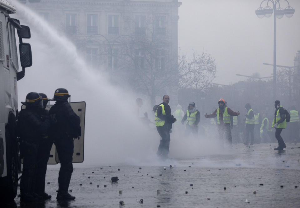 Demonstrators wearing yellow jackets face water cannons near the Champs-Elysees avenue during a demonstration Saturday, Dec.1, 2018 in Paris. French authorities have deployed thousands of police on Paris' Champs-Elysees avenue to try to contain protests by people angry over rising taxes and Emmanuel Macron's presidency. (AP Photo/Kamil Zihnioglu)