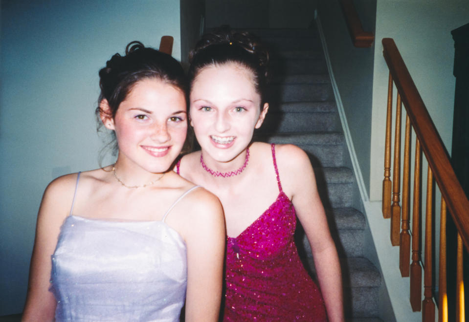 Two teenagers who are about to go to a school dance are posing for a picture