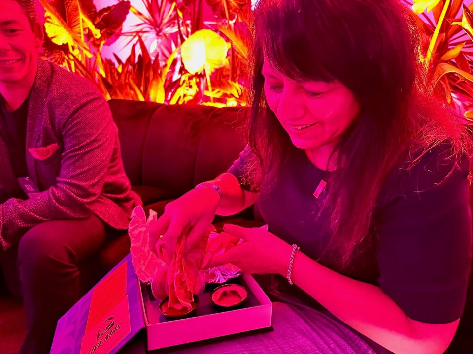 Nancy Luna sitting at a table in a neon-lit room with Taco Bell's Grilled Cheese Dipping Taco