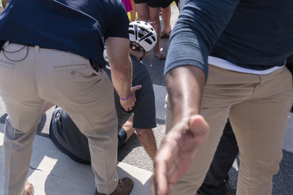 President Joe Biden is helped by U.S. Secret Service agents after falling from his bike as he stopped to greet a crowd on a trail at Gordons Pond in Rehoboth Beach, Del., Saturday, June 18, 2022. (AP Photo/Manuel Balce Ceneta)